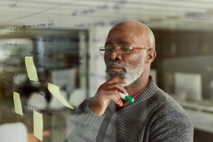 man in deep thought reading post-it notes