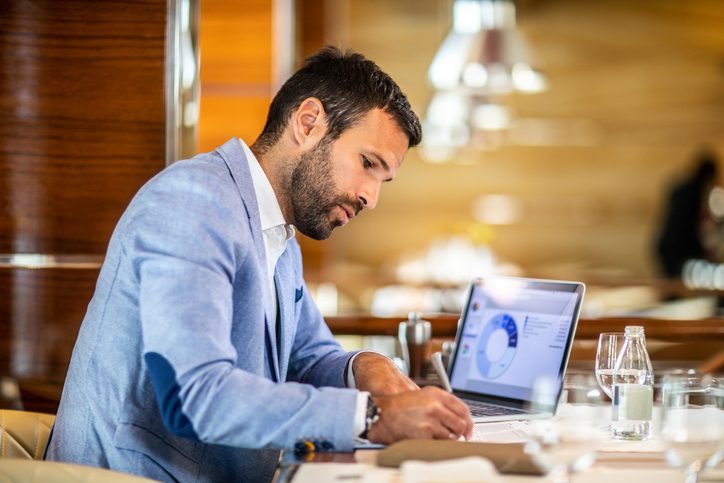 man making notes from his laptop