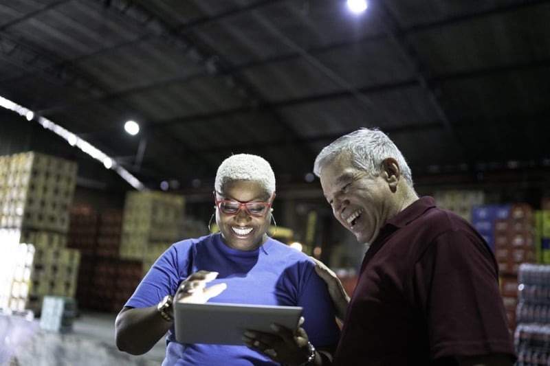 warehouse workers celebrating good news looking at a tablet