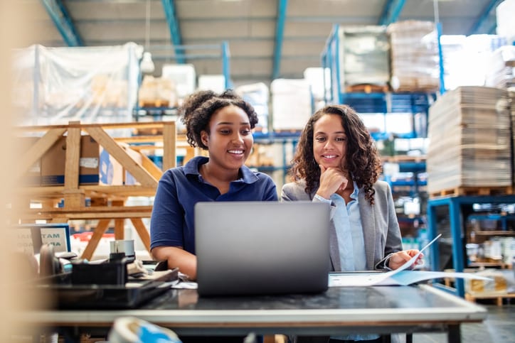 warehouse worker and manager smiling at laptop
