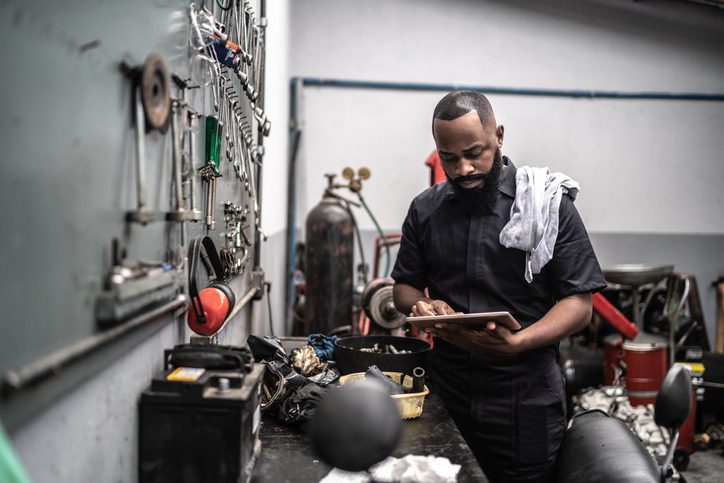 man in his workshop looking at his tablet