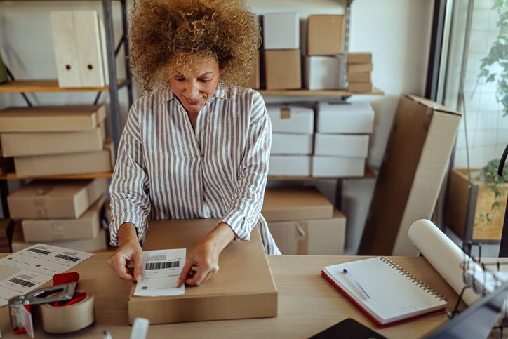 woman sticking delivery barcode on parcel