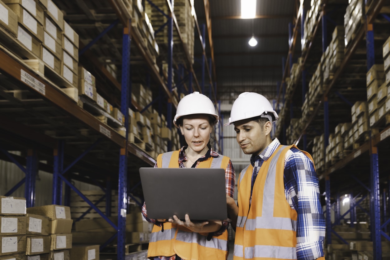 warehouse workers checking stock on laptop