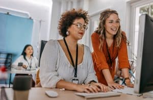 Two businesswomen working together on computer at office