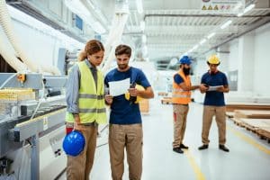 Employees working in modern factory with automated machines and robots for efficient production