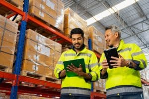 Workers checking goods stock on shelf in warehouse inventory using digital tablet.